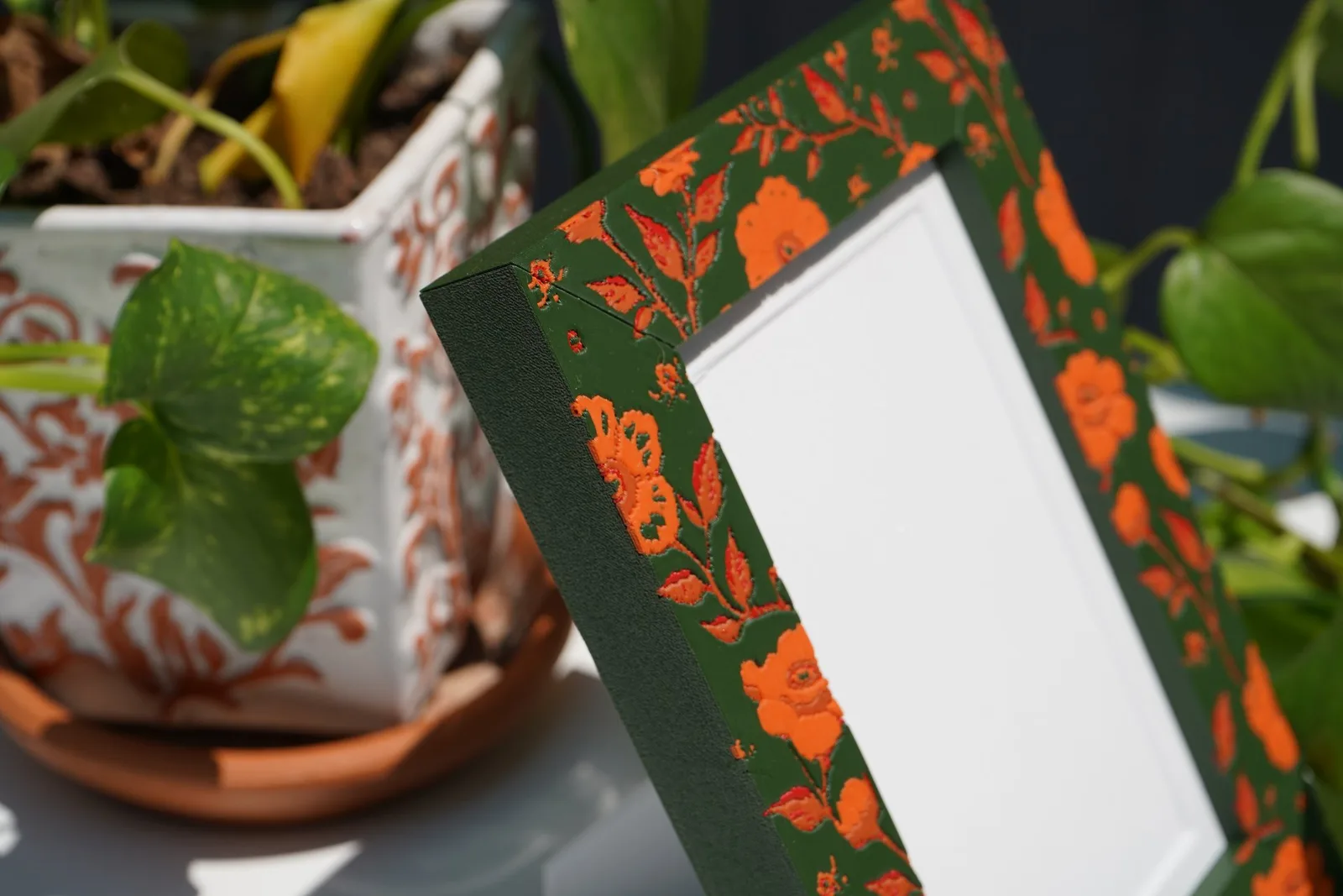 The same kind of pattern printed: orange florals in relief on a green frame