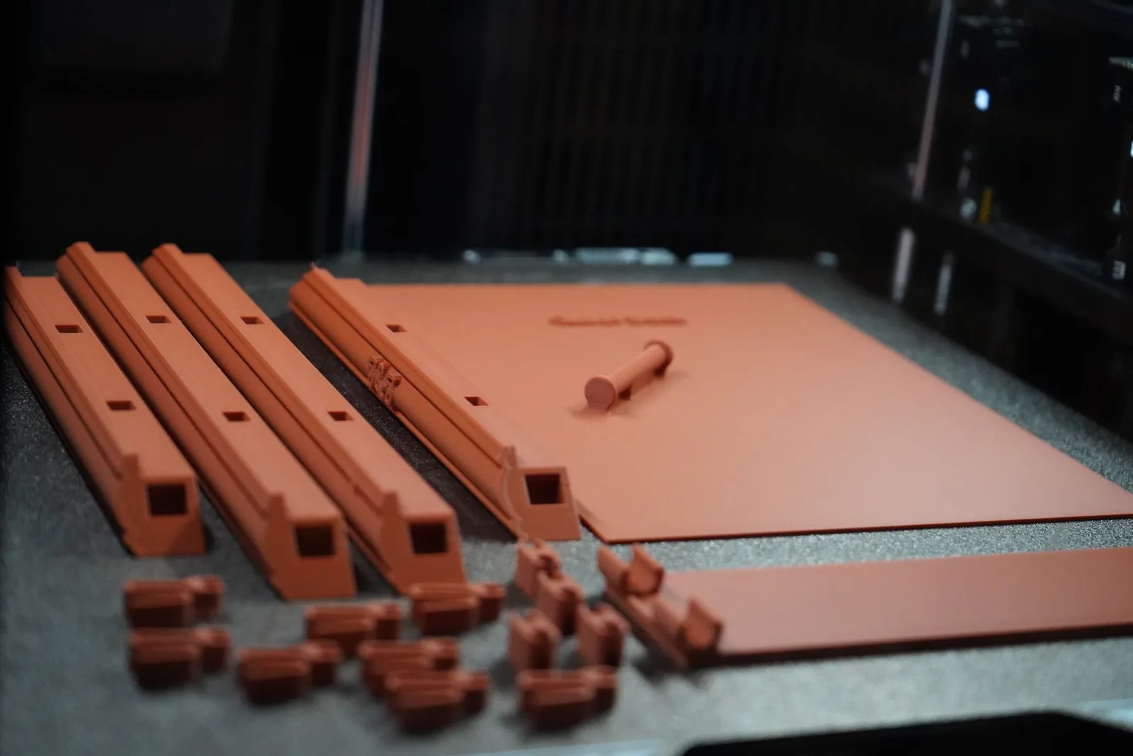 A complete snap kit laid out before assembly: four edge pieces, corner clips, prongs, backer plate, and kickstand